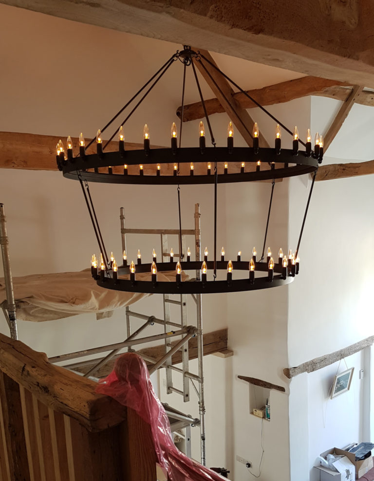 multiple candle lamps on large chandelier in barn conversion