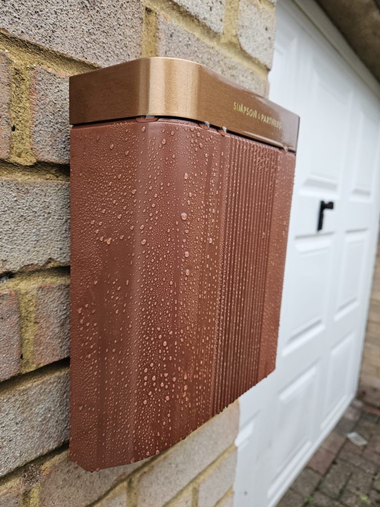 Side view of the copper charge point against the brickwork