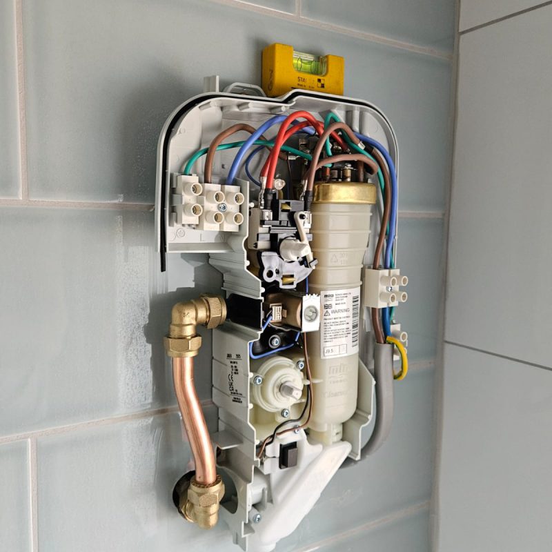 New shower unit open on the wall, copper pipework in and the supply terminated