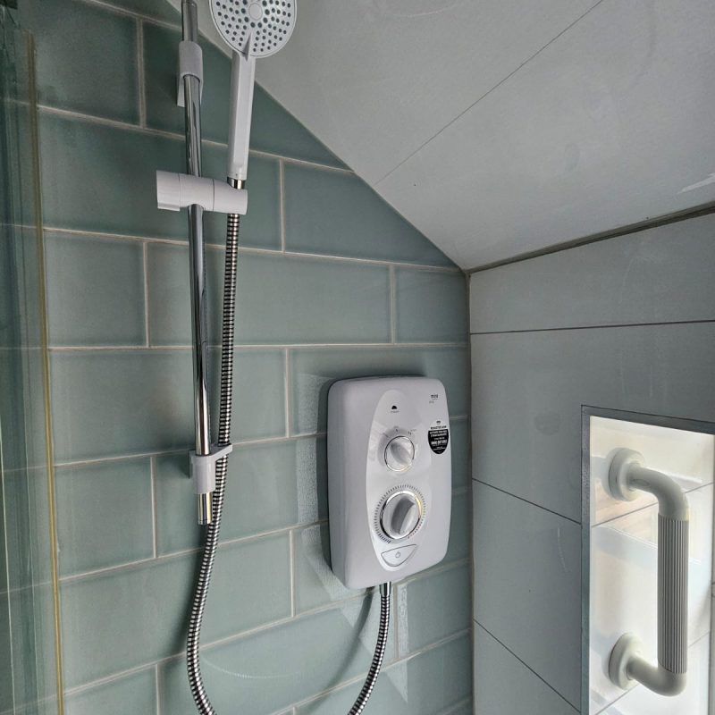 Wider view of the shower room, grab rail on the wall to the right